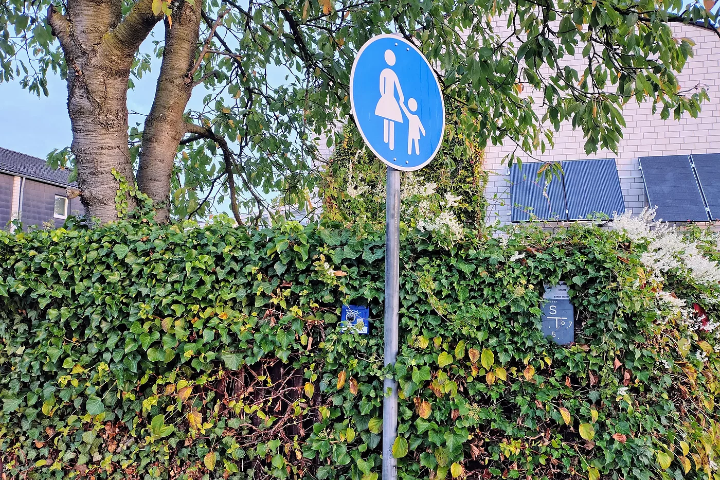 Schau genau hin: Der blaue Tresor-Geocache ist am Zaun des Zentralen Stützpunkt des ADFC Langenhagen angebracht, gleich links vom Mast des Fußgängerschildes.