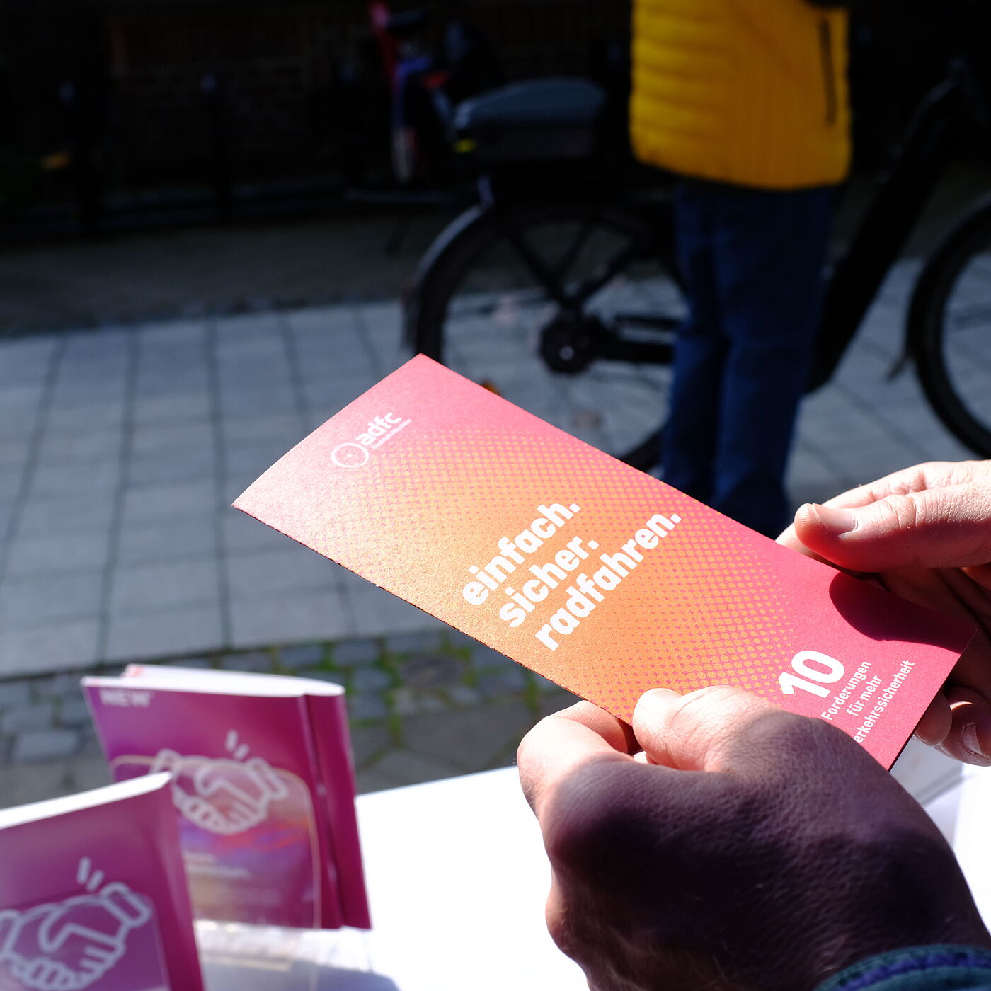 Eine Person hält einen Flyer.