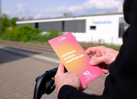 Eine Person hält einen Flyer in den Händen.