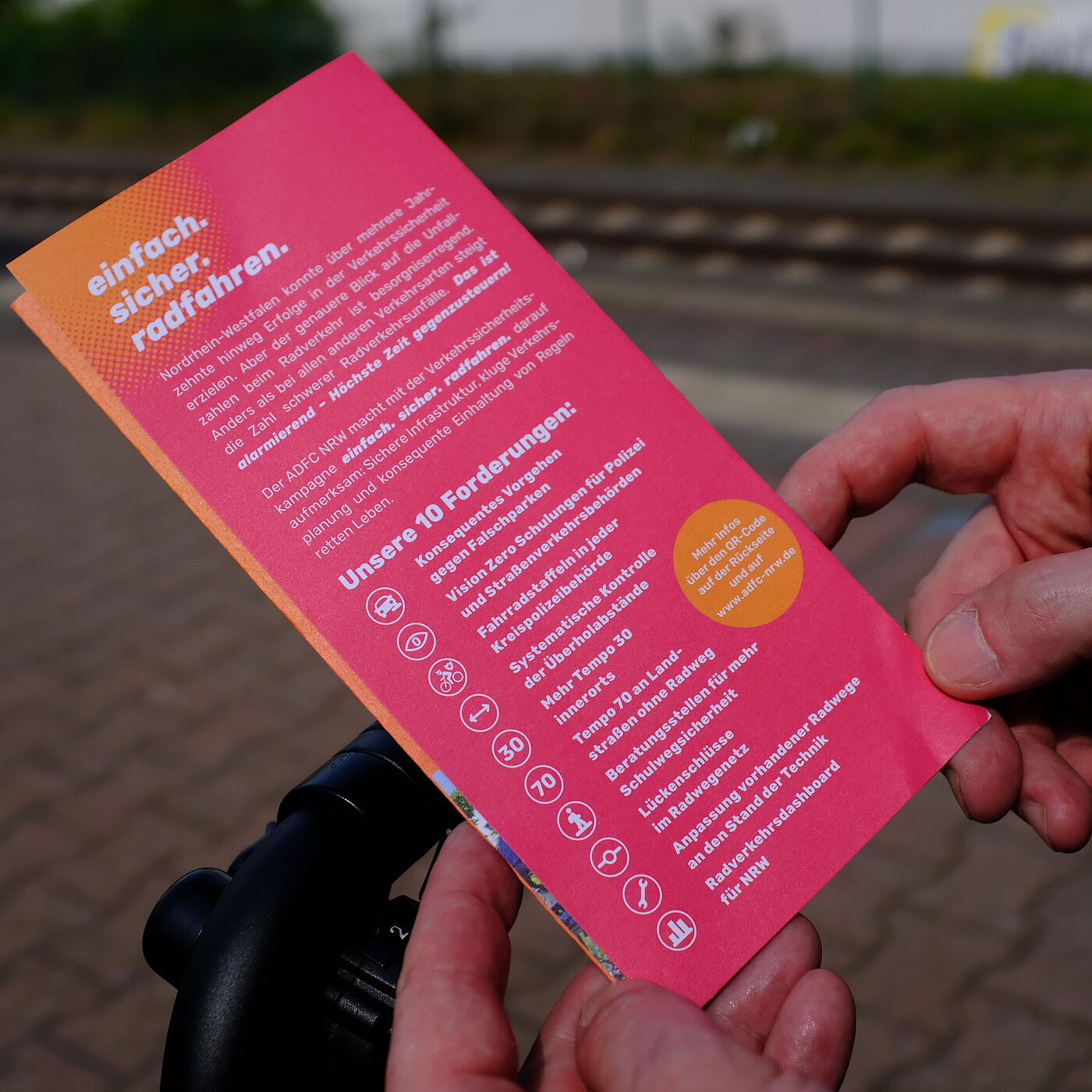 Eine Person hält einen Flyer in den Händen.